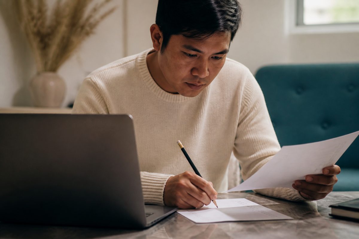 Someone working through a checklist beside a laptop
